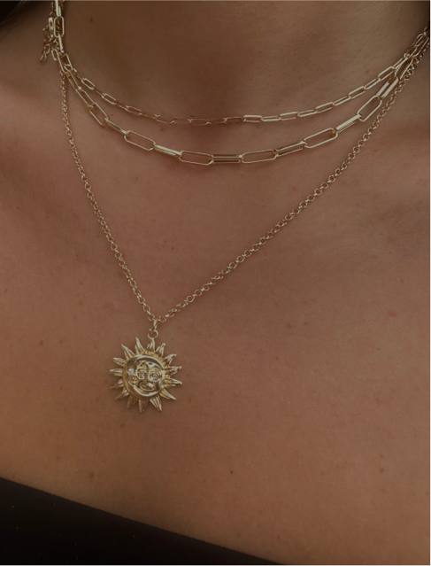 gold necklace stack with gold paperclip chains and a minimalist sun and moon pendant